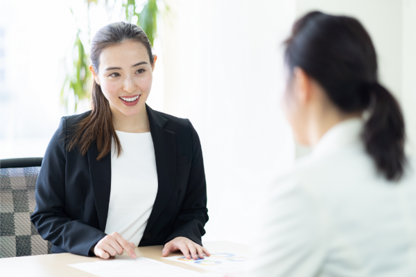 テーブル越しに会話するスーツ姿の女性